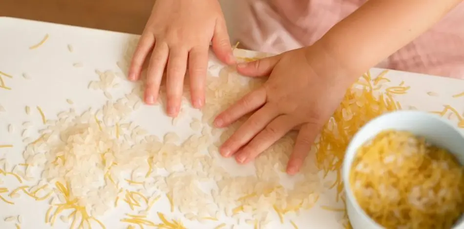 Dziecko bawiące się ziarenkami ryżu i makaronu